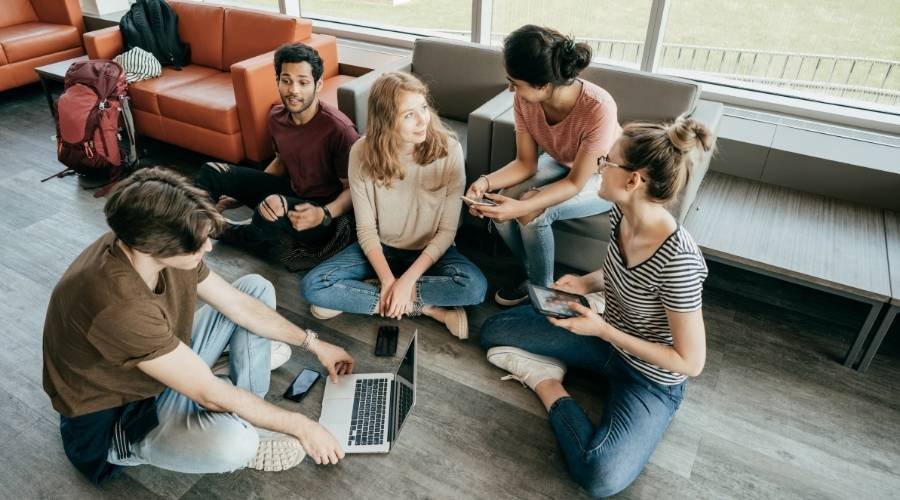 Group of friends studying with laptops and tablets.
