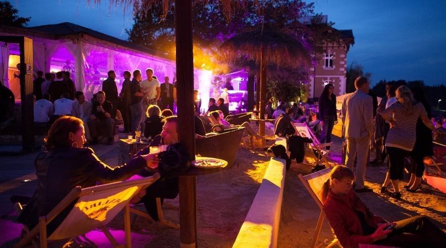 Outdoor evening beach party with colorful lights.