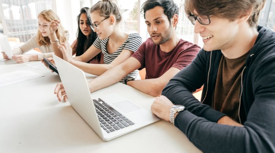 Group of students collaborating on laptop project.