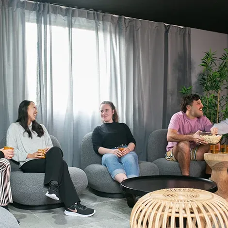Group of friends sitting and laughing together indoors.