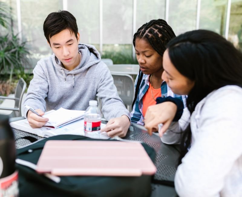 Students collaborating outdoors at a table.