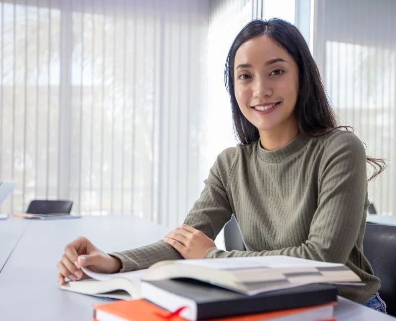Smiling woman studying at table indoors.
